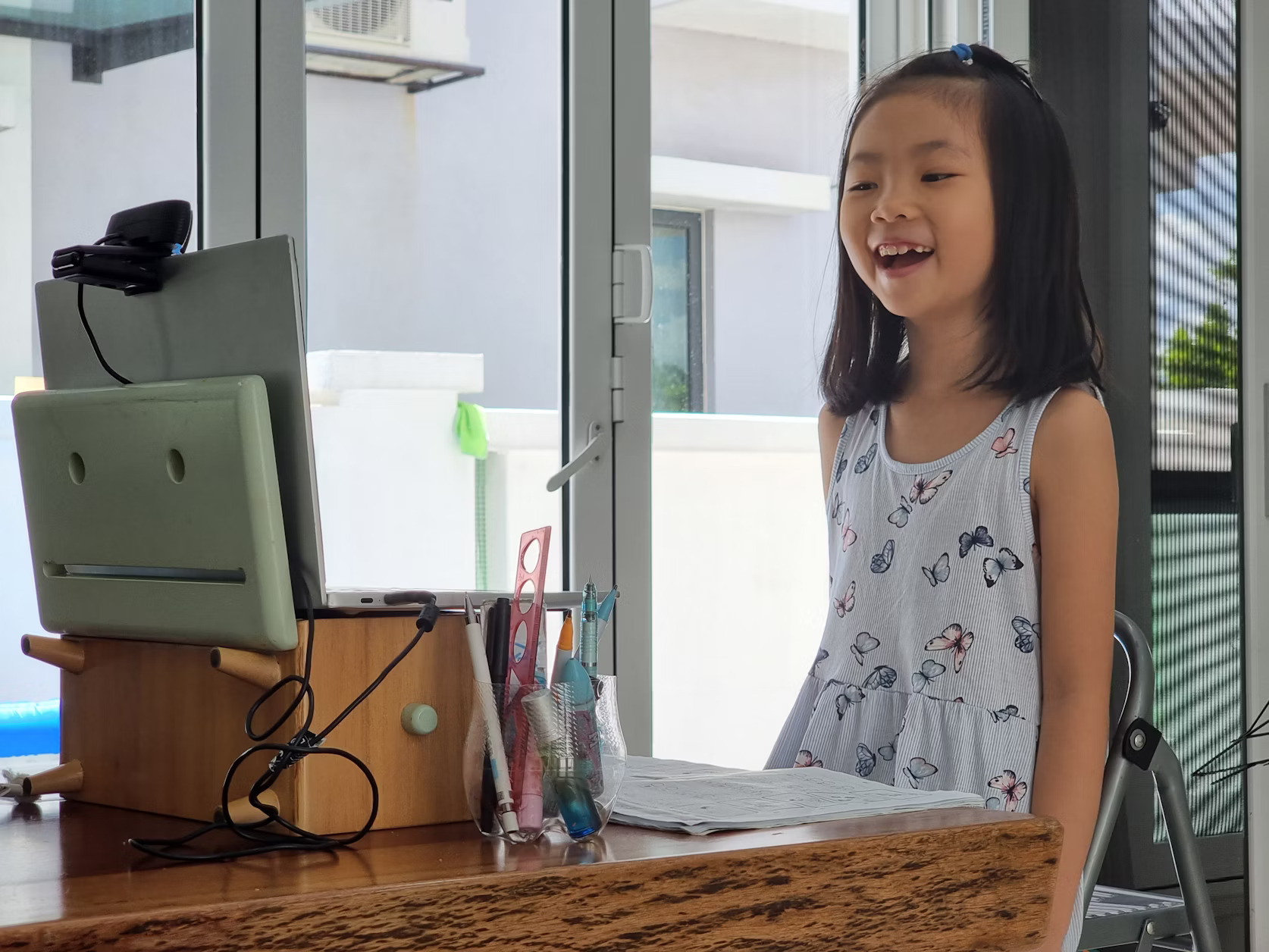 A young girl happily engaged in a video call on her laptop at home.